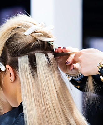 Tape Extensions being applied onto a woman's hair.