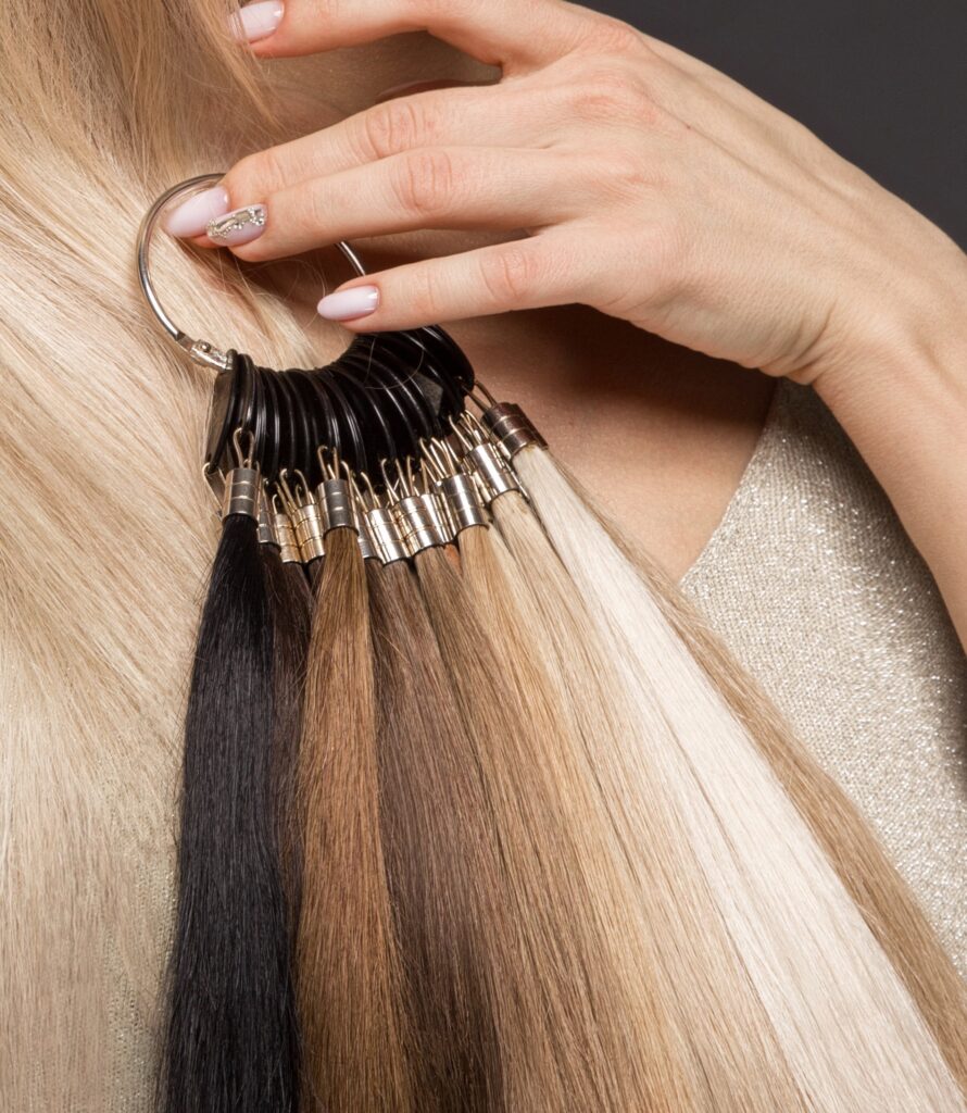 Beautiful blond girl with a perfectly smooth hair, classic make-up with a palette for hair extensions in the hands.